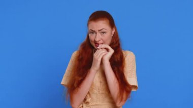 Stresli genç kızıl saçlı kadın tehlike sorunlarından korkuyor, fobisi var, anksiyete bozukluğu var, korkusunu dile getiriyor, hayır diyor, güvensizlik, stres, panik. Mavi stüdyo arka planında izole edilmiş kız
