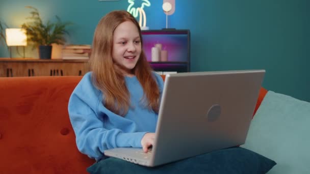 楽しい会話を楽しむ友人や家族とのビデオウェブカメラの会議コールを作る幸せな少女 笑顔の子供は 教師と話すためにノートパソコンを使用します ソファに座っている自宅での教育 — ストック動画
