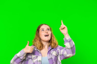 Başparmak gösteren ve boş yerleri işaret eden genç bir kadın ticari metinler için reklam alanı, ürün tanıtım reklamları için kopyalama alanı. Krom anahtar arka planında izole edilmiş bir kız. Yaşam Tarzları