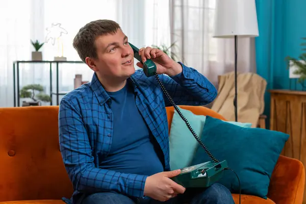 stock image Portrait of young Caucasian fat man making telephone conversation with friends sitting on comfortable couch at home. Happy excited guy male enjoying old-fashioned retro phone from 90s talking indoors