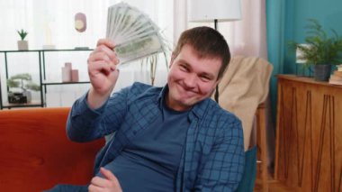 Zengin, Kafkasyalı, zengin, zengin, genç bir adam. Yüksek kazanç, piyango oyunu kazancı, servet kazanma maaşı. Oturma odasında kanepe dolusu nakit para, daire banknotları..