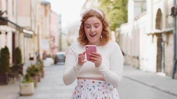 Akıllı Telefon Kutlaması Yapan Mutlu Genç Kızıl Saçlı Bir Kız — Stok video