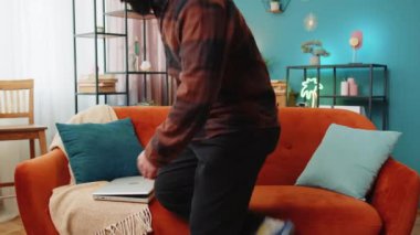 Hintli bir adam odaya girer dizüstü bilgisayarda yazmaya başlar. İnternette gezinir. Uygulamalar kanepede oturur. Evdeki bilgisayarda çalışan mutlu İspanyol genç adam. Not defterindeki e-öğrenme interneti