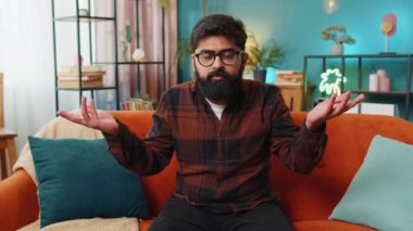 Ne diyecegimi bilmiyorum. Kafası karışmış Hintli Arap bir adam belirsiz bir sorudan utanıyor, kuşkuları var, hiçbir fikri yok, bilgisiz ve kararsız. Genç üzgün Hintli adam kanepede oturuyor.