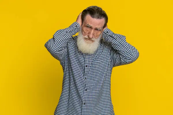 Dont want to hear and listen. Frustrated annoyed irritated senior old man covering ears gesturing no, avoiding advice ignoring unpleasant noise loud voices. Grandfather isolated on yellow background