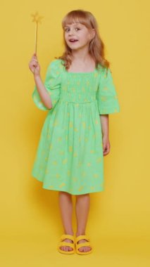 Sihirli değnek ve sihirli değnekle hareket eden büyücü kız cadı dileği gerçekleştiriyor, sihirbaz büyüsü yapıyor, indirimli tatil indirimi yapıyor. Çocuk sarı arka planda izole edilmiş. Dikey