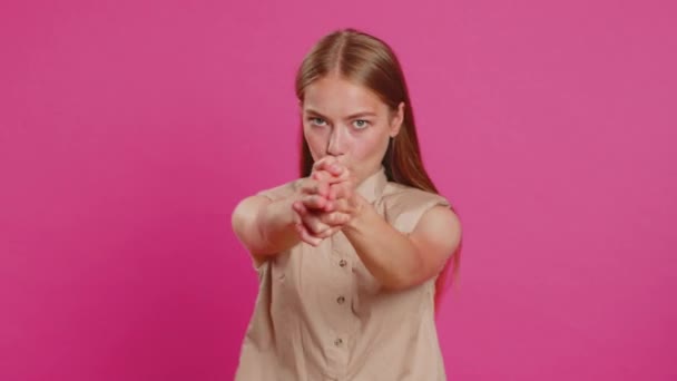年轻女人用手指举枪指指点点 看起来很自信 做出选择 用手枪对着目标射击 女孩孤身一人在粉红工作室背景 生活方式 — 图库视频影像