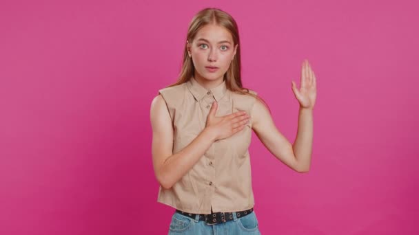 正直に誓った 誠実な責任ある若い女性は 正直であることを約束し 真実を伝えるために手を挙げ 胸に手をつないでください ピンクのスタジオで孤立した少女 ライフスタイル — ストック動画