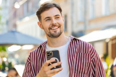 Mutlu, beyaz sakallı, akıllı telefon kullanan internet sosyal medya uygulaması üzerinden mesaj yazan açık havada sohbet eden bir adam. Şehir caddesinde yürüyen bir turist. Yaşam Tarzları