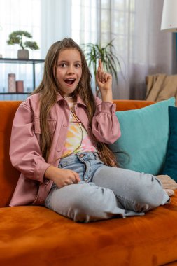 Evreka. İlham verici kız iyi bir fikir, plan, başlangıç, ilham verici motivasyon hareketi, problem çözümü gösteriyor. Evdeki oturma odasındaki kanepede oturan şık çocuk.