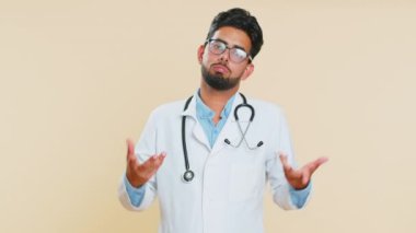 Ne diyecegimi bilmiyorum. Kafası karışmış Hintli genç doktor kardiyolog belirsiz bir soru hakkında mahcup hissediyor, şüpheleri var, cevap yok, hiçbir fikri yok. Bej arka planda Arap eczacı.