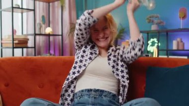 Başarılı beyaz kadın elinde dolar banknotları tutan bir hayranla sınıftaki kanepede oturuyor. Mutlu heyecanlı kız çevrimiçi kumarhane oyunu kazanıyor tatil planlama evde bütçe hesaplama.