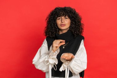 Biraz daha, lütfen bana ver. Kıvırcık saçlı beyaz bir kadın, kuşkucu bir gülümseme sergiliyor, minimum boyda, yalvarıyor. Kırmızı arka plandaki kız