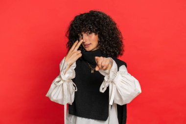 Gözüm üzerinde. Özenli, beyaz, kıvırcık saçlı, gözleri ve kamerası olan genç bir kadın. Seni birini gözetlerken izlediğimi göster. Katı kız kırmızı arka planda izole edilmiş.