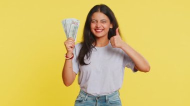 Zengin, mutlu, Hintli genç bir kadın hayranı, başarılı bir iş adamı, piyango talihlisi, büyük gelir getiren banknotlar sallıyor. Sarı arka planda izole edilmiş Arap Hindu kız