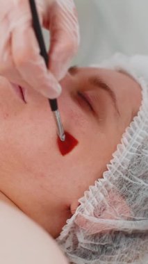 Güzellik tedavisi, enzim terapisi. Yetenekli bir güzellik uzmanı, genç bir kadının yüzüne, yanaklarına odaklanarak, tıbbi krem maske takıyor. Genç cilt bakımı için kaplıca bakım prosedürü