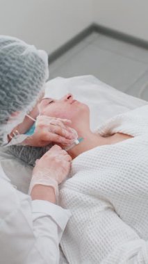Güzellik yaşlanmayı önleyici enjeksiyonlar biyo-evrizasyon boyun mezoterapisi ile karşılaşıyor. Kozmetik doktoru genç bir kızın derisine iğne kolajen enjeksiyonu yapıyor. Klinikte prosedür terapisi