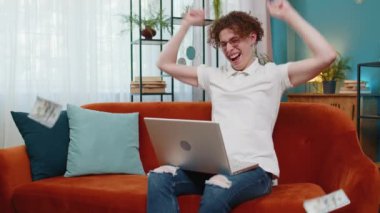Kafkasyalı bir adamın üzerine para yağmuru yağıyor laptopta çalışıyor başarıyı kutluyor, kazanıyor, gol başarısı, iyi haber piyango ikramiyesi. Kariyer büyür. Oturma odasındaki kanepede oturan genç adam.