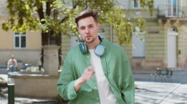 Sessiz olun lütfen. Esmer genç adam işaret parmağını dudaklarına bastırıyor. Sessiz ol işareti yapıyor. Dışarıdaki dedikoduları kimseye söyleme. Genç erkek, şehir caddesinde duruyor. Kasaba yaşam tarzları.