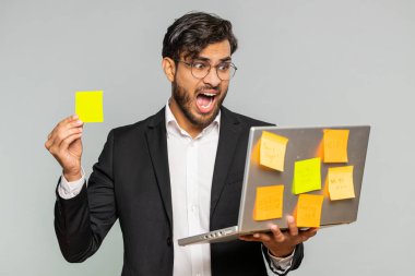 Yapıştırmalı notları olan bitkin Hintli işadamı dizüstü bilgisayar kullanıyor. Konsantrasyon sorunu olan yaratıcı kriz. Resmi takım elbiseli gergin erkek Arap adam büyük rutin iş yüklemesi yüzünden kafası karışmış.