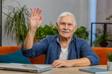 Hoş geldiniz. Kıdemli adam el sallayarak kameraya gülümsüyor merhaba diyor evde misafirperver bir yüz ifadesiyle hoş geldin diyor. Yaşlı, olgun büyükbaba masada koltukta oturuyor.