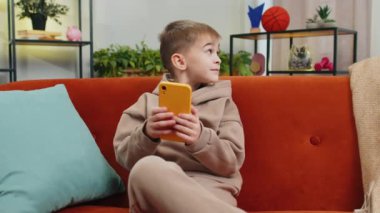 Akıllı telefon sosyal medya uygulamaları üzerinden rahatlama filmi izlerken mesajlaşan genç çocuk. Beyaz bir erkek çocuk evde cep telefonu kullanıyor. Oturma odasında, koltukta oturuyor.