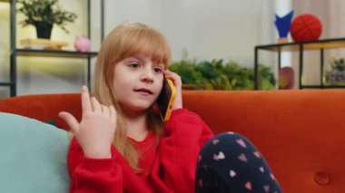 Telefon, iyi haber, dedikodu. Akıllı telefondan hoş sohbetler yapan, çocukluk çağındaki mutlu bir kız çocuğu arkadaşıyla konuşmaktan zevk alıyor. Genç bayan küçük çocuk evdeki kanepede oturuyor.