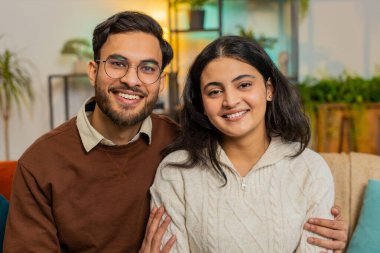 Kameraya bakıp gülümseyen, kanepede oturup rahatlayan genç ve çeşitli çiftleri seven bir çift. Mutlu İspanyol ailesi boş zamanlarını evdeki oturma odasında kameraya bakarak geçiriyor..