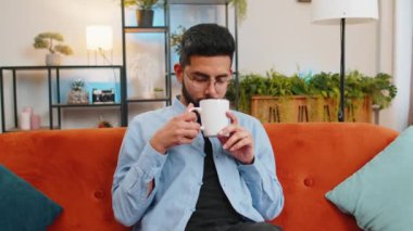 Yakışıklı, gülümseyen Hintli adam sabahları bir fincan sıcak kahve ya da bitki çayı içiyor. İspanyol adam ferahlatıcı keyfini çıkarıyor. Evde, turuncu koltukta tek başına rahatlıyor..
