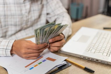 İş adamlarının yakın çekim elleri nakit paraları sayıyor maaşları kontrol ediyor modern işyerlerinde zenginliğin tadını çıkarıyorlar. Merkez büro masasında para kazancı hesaplayan mutlu serbest çalışan adam..