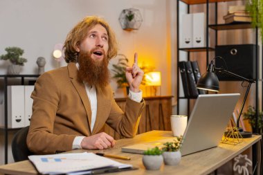 Genç Kafkasyalı girişimci sunum için başlangıç projesini hazırlıyor ve fikri buluyor. Kendine güveni tam bir serbest çalışan ofis masasında dizüstü bilgisayarla yazı yazmayı düşünüyor. Uzak çalışma.