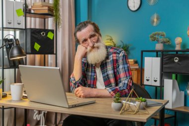 Düşünceli, düşünceli, Kafkasyalı kıdemli bir adam ofisteki masada dizüstü bilgisayarla ilgili bir sorun düşünüyor. Ciddi büyükbaba. İlham arayışı içinde. Düşüncelerin eksikliğini hisset..