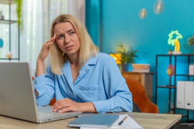 Baş ağrısı, gerginlik, migren, iş yerindeki stresten muzdarip yorgun genç iş kadını. Dizüstü bilgisayarla çalışan sarışın, serbest çalışan kadın. Fazla çalışma.