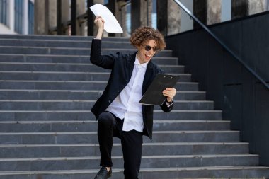 Başarılı, mutlu, beyaz, erkek, işadamı, kazanan, girişimci, patron, zafer kutlamaları için ofis binasının yakınlarına kağıt dökümanlar at..