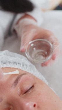 Kozmetik uzmanı, özel nemlendirici asit kokteyli uyguluyor. Kadının gözlerinin etrafına yüz derisi soyuluyor. Güzellik salonunda yüz bakımı yaşlanmayı önleyen kozmetik tedavi prosedürü. Kırışıklıklar gideriliyor