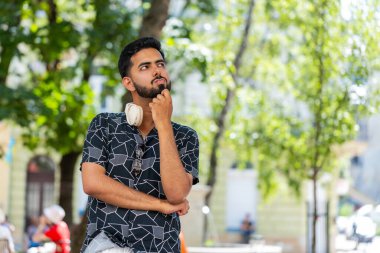 Düşünceli, düşünceli, düşünceli, düşünceli, genç Hintli bir adam. Düşünceli bir ifadeyle, bir çözüm düşünüyor, şüpheci bir soru soruyor, dışarıda hayaller kuruyor. Sakallı Hintli adam şehir caddesinde. Kasaba yaşam tarzları.