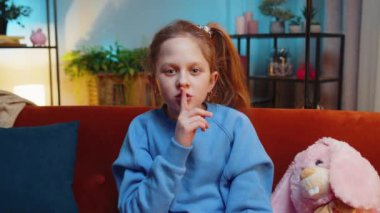 Sessiz olun lütfen. Ergen kız işaret parmağını dudaklarına bastırıyor. Sessiz ol işareti yapıyor. Dedikodu sırrını kimseye söyleme. Genç bayan çocuk evde akşam odasında kanepede oturuyor.