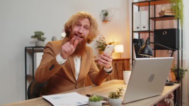 Kendine güvenen kızıl saçlı işadamı internet üzerinden akıllı telefon uygulaması kullanarak konuşuyor. Onaylıyor, uzaktan kumandayla çalışıyor. Kameraya bakan serbest çalışan bir adam. Reklamcılık