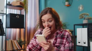 Akıllı telefon üzerinde çalışan genç ve şaşkın iş kadını aniden kazanılan piyango galibiyeti ile şok oldu. Kariyer başarısı iyi haber. Ofis masasında oturan heyecanlı serbest çalışan kadın..