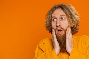 Aman Tanrım. Vay canına. Heyecanlı kazanan adam şaşkınlıkla el kaldırıyor kameraya büyük gözlerle bakıyor başarıyı kutlayan zaferin şokuyla iyi haberleri kutluyor. Turuncu arka planda kızıl saçlı adam.