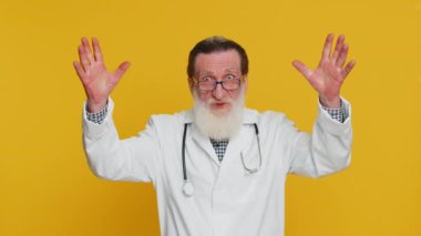 Elleriyle beyin patlaması jesti, çözüm, ilham, başarı beyin fırtınası yapan heyecanlı kıdemli doktor kardiyolog. Eczacı dedesi sarı arka planda izole edilmiş.