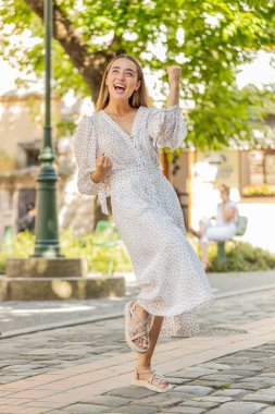 Heyecanlı mutlu kadın gezgin bağırıyor, başarıyı kutluyor, kazanıyor, gol başarısı, iyi haber, piyango talihi, açık havada zafer. Şehir Güneşi Sokağı 'nda yürüyen genç bir bayan. Yaşam Tarzları