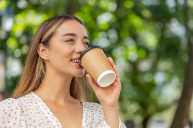 Kafkasyalı genç ve güzel bir kadın sabah kahvesinin tadını çıkarıyor sıcak bir şeyler içiyor ve dışarıda gülümsüyor. Dinleniyorum, ara veriyorum. Şehir merkezindeki caddede durmuş, kahve içen bir kız. Kasaba yaşam tarzları.