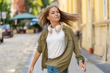 Şehir caddesinde yan yana yürüyen, tasasız, mutlu, beyaz kadın portresi. Rahatlama, dışarıda mutlu bir ifade. Genç kız turist. Kasaba yaşam tarzı.