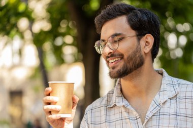 Mutlu Hintli adam sabah kahvesinin tadını çıkarıyor sıcak içecek ve gülümsüyor. Dinleniyorum, ara veriyorum. Şehir merkezindeki caddede dikilen Latin kökenli genç adam kahve içiyor. Dışarıdaki kasaba yaşam tarzları.
