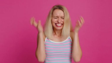 Irritated angry Caucasian young woman 30 years old screams from stress tension problems feels horror hopelessness fear surprise shock expresses rage nervous, quarrel. Girl isolated on pink background