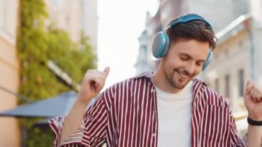 Neşeli, sakallı, kablosuz kulaklıkla dans eden, açık havada favori disko rock 'n roll müziğini dinleyen mutlu yetişkin adam. Şehir Günışığı Sokağı 'nda duran genç adam.