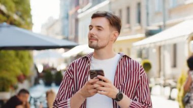 Mutlu, esmer, sakallı, akıllı telefon kullanan internet sosyal medya uygulamasına girip mesaj yazan açık havada sohbet eden bir adam. Şehir caddesinde yürüyen bir turist. Yaşam Tarzları
