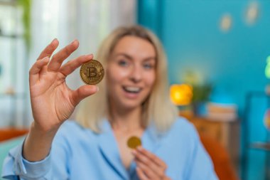 Çevrimiçi ticaret operasyonlarını izledikten sonra bitcoin kazanan genç sarışın işkadını borsacı. Zenginliğin finansal refahı artıyor. Serbest çalışan kadın odadaki masada BTC şifreleme paraları gösteriyor.