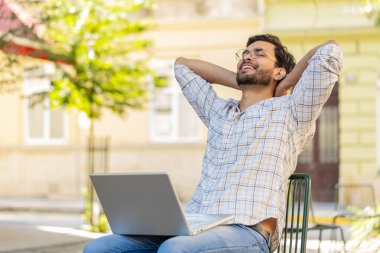 İskemlede oturan Hintli serbest çalışan bilgisayar ekranını kapatıyor uzaktan iş görüşmelerini bitiriyor, web sitesinde sohbet ediyor, kameraya bakıyor. Adam netbook kullanıyor, mesajlar gönderiyor, açık havada film seyrediyor.